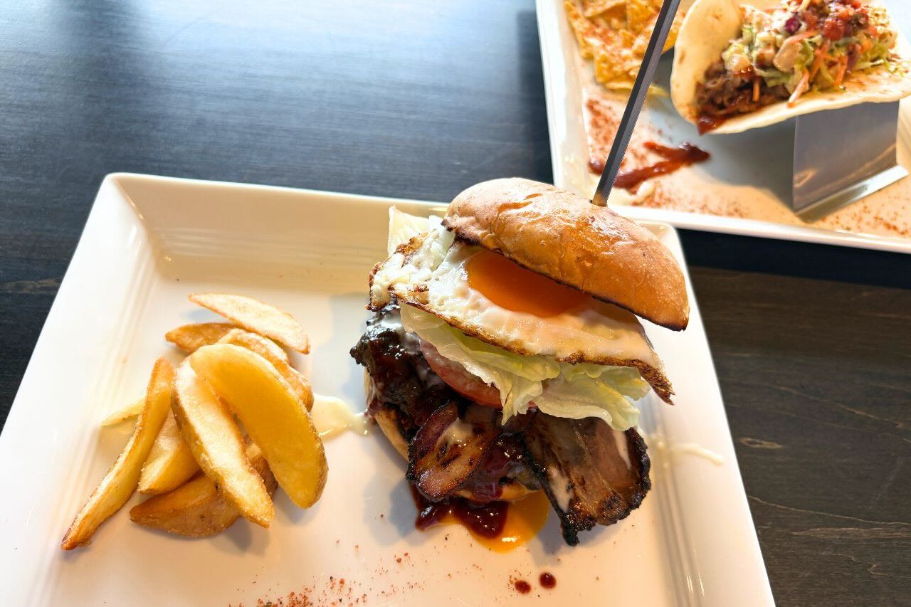 炭火かおるアメリカンダイナー「GRILL JOCKEY（グリル ジョッキー）」の薩摩黒豚100％の贅沢バーガーにかぶりつく（沖縄市）